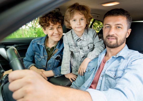 happy-young-contemporary-family-three-denim-jackets-looking-you-with-smiles-while-sitting-car-going-countryside-min